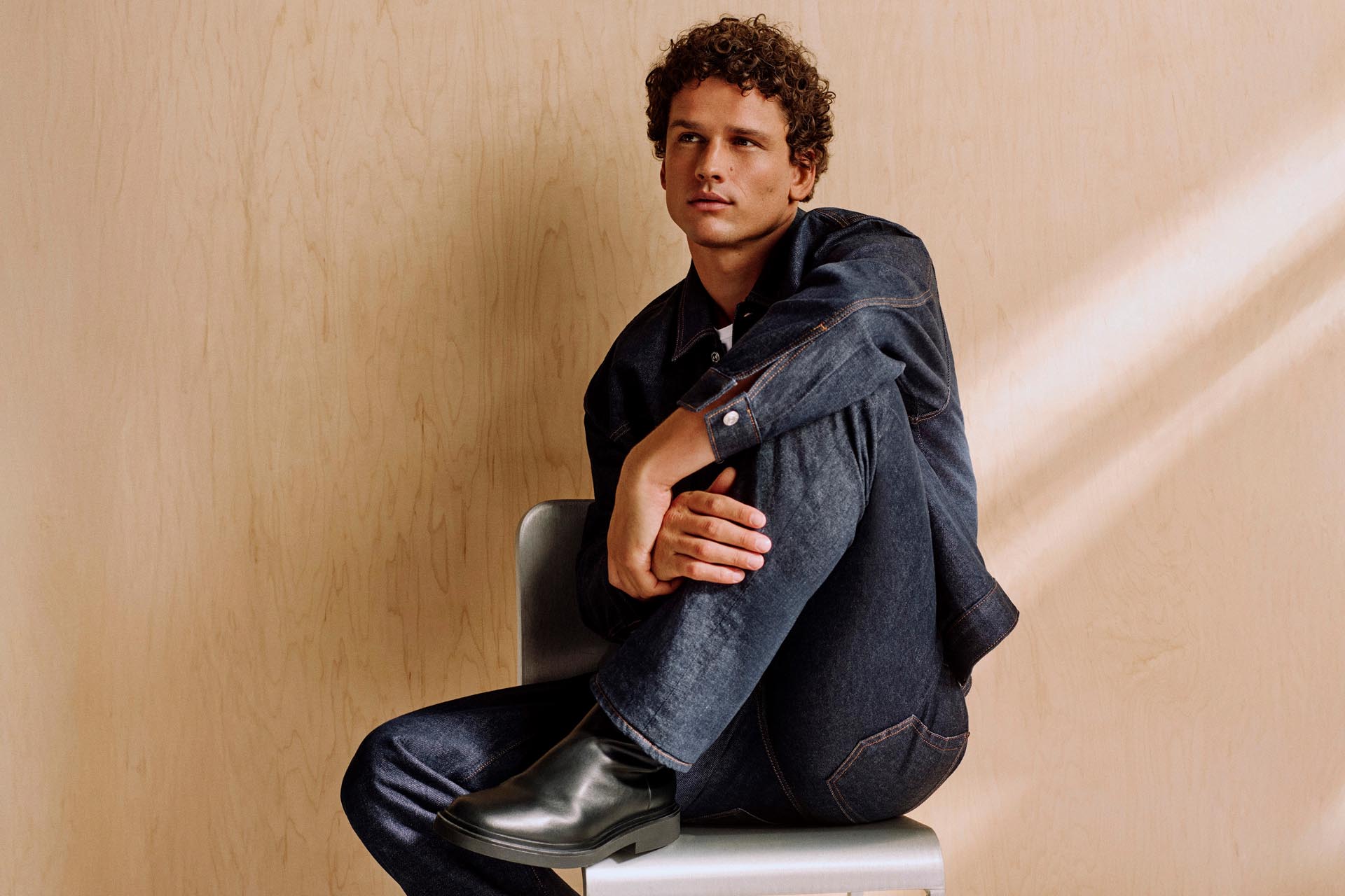 Model posing in a dark denim jacket and jeans