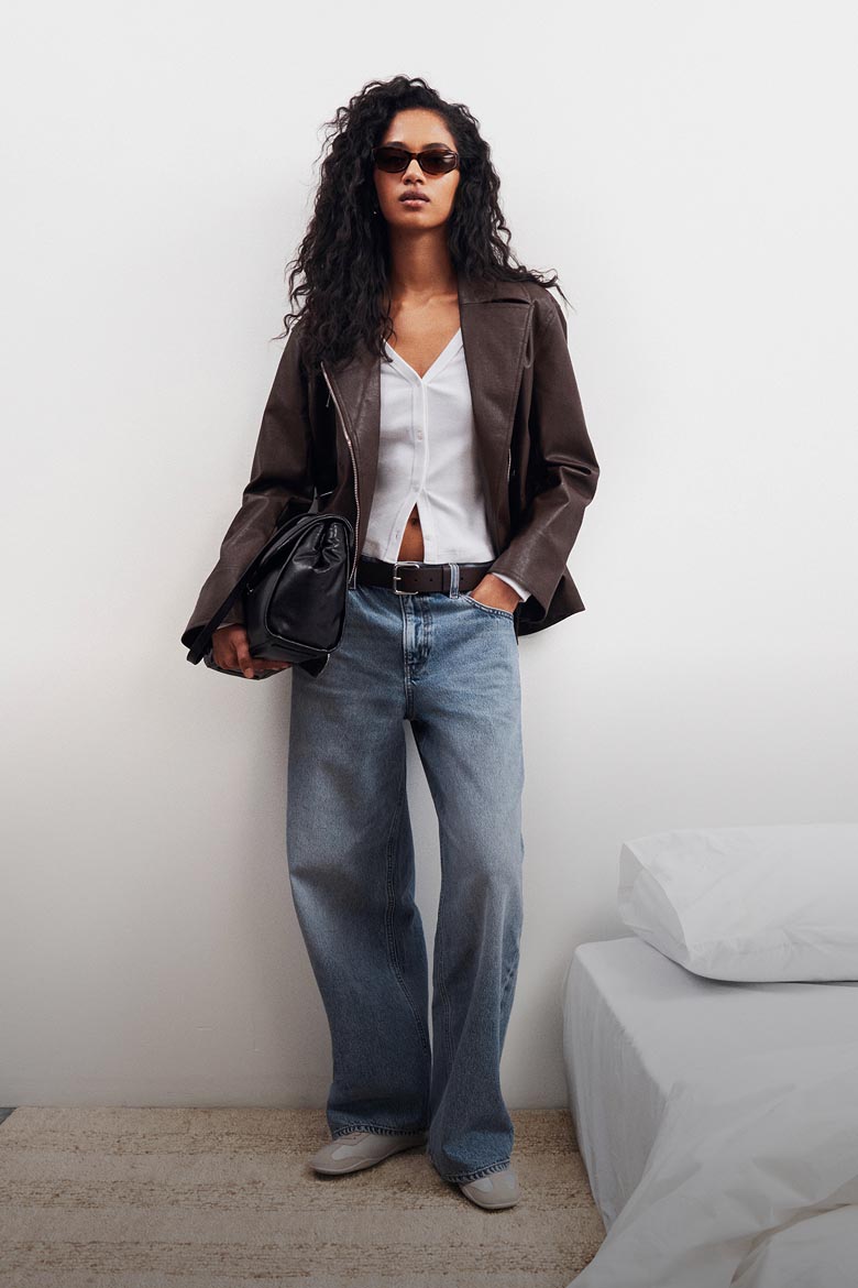 Model posing in a brown leather bomber jacket