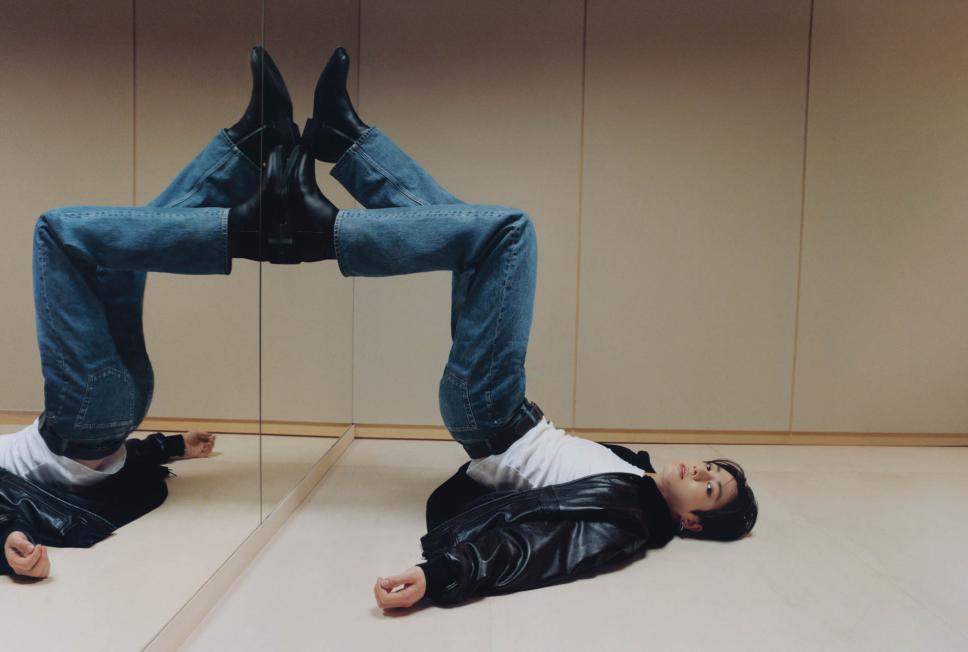 Jung Kook posing in 90s Straight jeans and a black leather bomber jacket