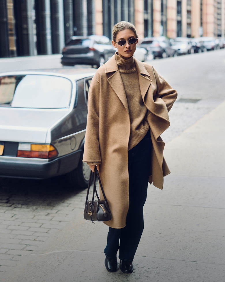 Model posing in a tan wrap coat