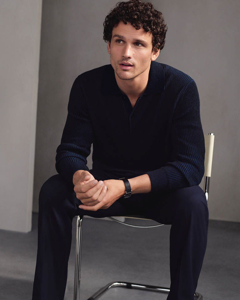 Model posing in a black relaxed polo sweater