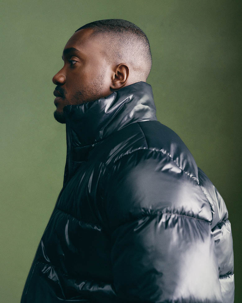 Sebastian Jean posing in a green puffer jacket