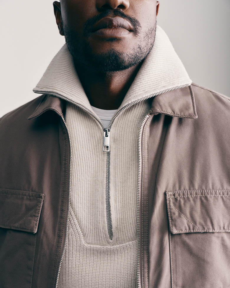 Sebastian Jean posing in an oatmeal quarter zip sweater