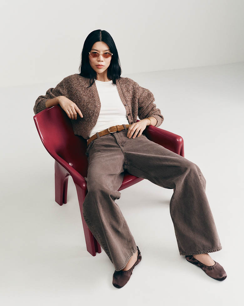 Jessa Choi posing in a tan cardigan and brown jeans