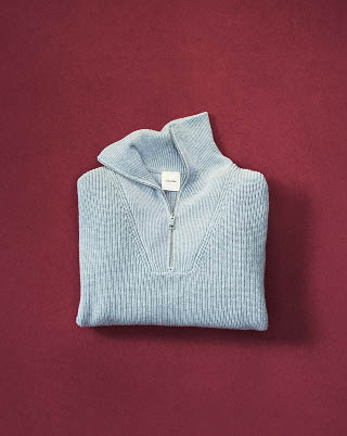 Still life image of a grey quarter zip sweater