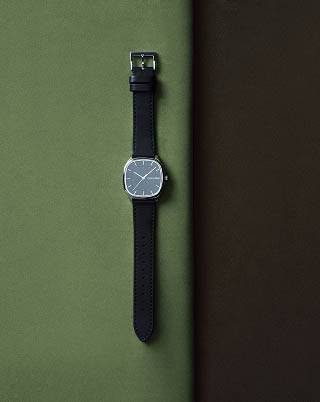 Still life image of a black leather watch