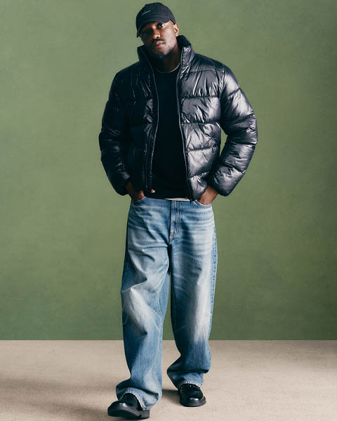Sebastian Jean posing in a short black puffer jacket and jeans